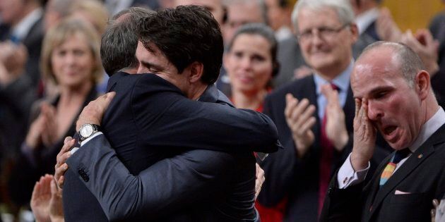Prime Minister Justin Trudeau hugs Liberal MP Rob Oliphant as MP Randy Boissonnault wipes a tear after making a formal apology in the House of Commons to individuals harmed by federal policies that led to discrimination against LGBTQ2 people in Canada on Nov. 28, 2017.