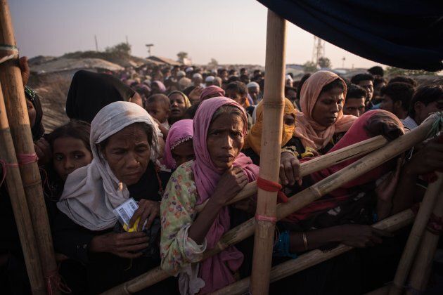 Rohingya Muslim refugees wait to be called to recieve food aid of rice, water and cooking oil in a relief centre at the Kutupalong refugee camp on Nov. 28, 2017.