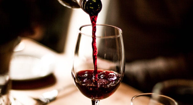 Red wine being poured into a stem glass at the table.