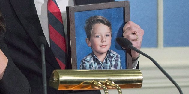 John Sutherland holds up a photo of his son Callum during a news conference with his wife Carly Sutherland at the legislature in Halifax on Thursday, Nov. 30, 2017.