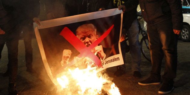 Palestinian protesters burn pictures of U.S. President Donald Trump at the manger square in Bethlehem on Dec. 5, 2017.