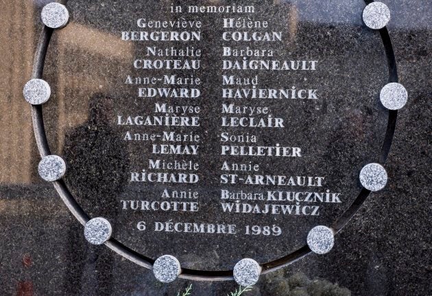 A man is seen reflected in the commemorative plaque during a ceremony marking the 28th anniversary of the Montreal Massacre.