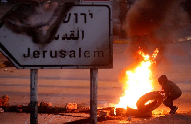 A Palestinian protester sets up a burning barricade near the West Bank city of Ramallah Dec. 8, 2017.