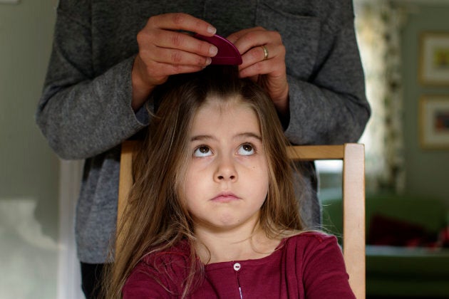 A mother checking her daughter's hair for head lice using a nit comb.