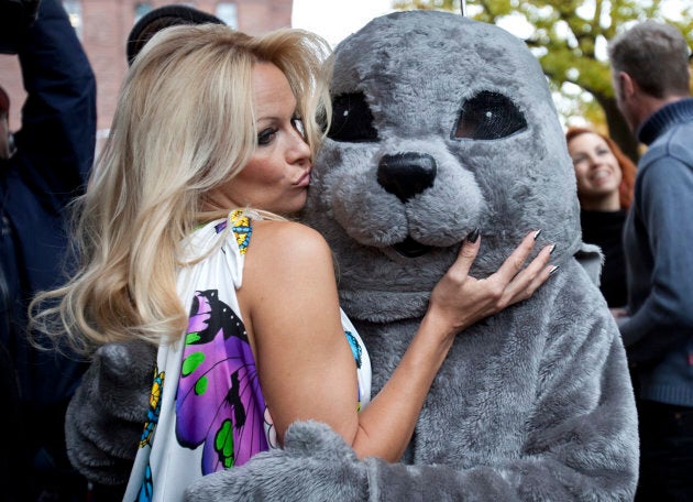 Pamela Anderson poses with a person dressed as a seal as part of PETA's protest of the Canadian seal hunt at Queen's Park in Toronto, Oct. 23, 2009.