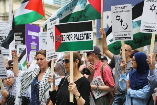 Protestors hold signs during a pro-Palestinian demonstration in Toronto on July 29, 2017.