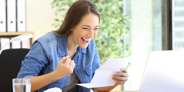 Excited casual entrepreneur girl reading good news in a letter in a desktop at office