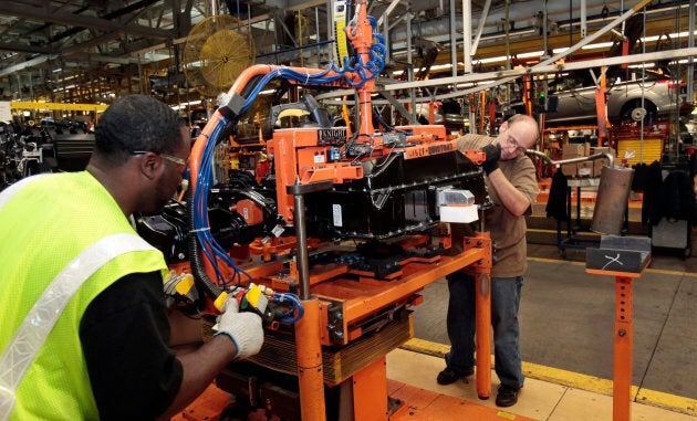 Ford assembly workers install a battery onto the chassis of a Ford Focus electric vehicle.