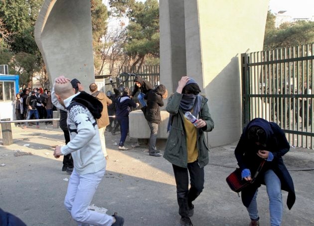 In this photo taken on Dec. 30, 2017, by an individual not employed by the Associated Press and obtained by the AP outside Iran, university students run away from stones thrown by police during an anti-government protest inside Tehran University, in Tehran.