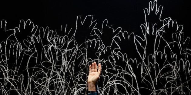 A woman holds up her hand as she waits to be silhouetted with white chalk during a performance by Spanish Artist Irisarri at ARCO, the international contemporary Art fair in Madrid, Spain, Friday, Feb. 27, 2015. The ARCO art fair will run from Feb. 25 to March 1, 2015. (AP Photo/Daniel Ochoa de Olza)