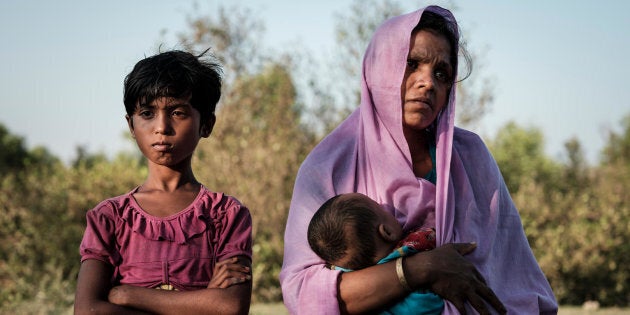 Rohingya refugee Mariom Khatun, 25, holds her baby Firuz Ahmed, 5 months, as they rest on the banks of the Naf River following a six-hour ordeal crossing the river on a makeshift raft made of bamboo and empty plastic oil containers tied together with rope, in Cox's Bazar District, Bangladesh.