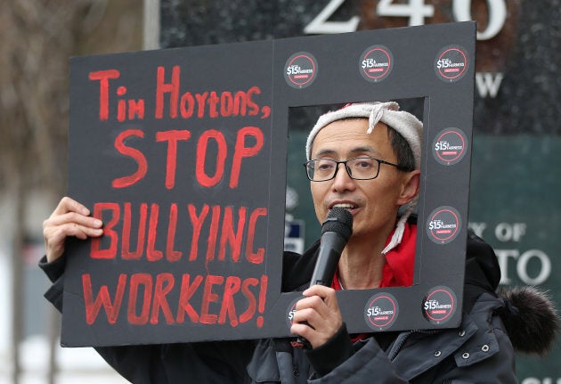 Protesters hold signs outside a Tim Horton's location in Toronto.