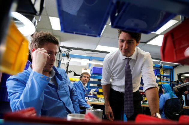 Prime Minister Justin Trudeau (R) talks to employees as he tours Kinova Robotics, a company that designs and manufactures robotic arms, in Boisbriand, Que. March 24, 2017.