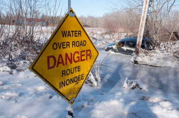 A minivan sits frozen in the water next to Route 101 in Blissville, N.B., on Jan. 14, 2018.