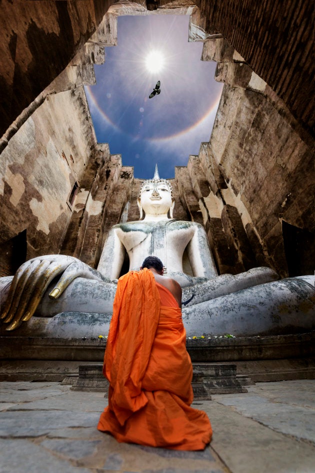 Monks worship Buddha statue Wat Si Chum in Sukhothai historical park, Thailand.