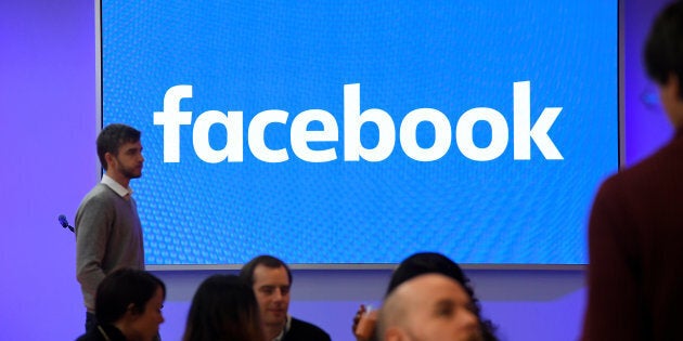 People stand in front of a logo at Facebook's headquarters in London, Dec. 4, 2017.