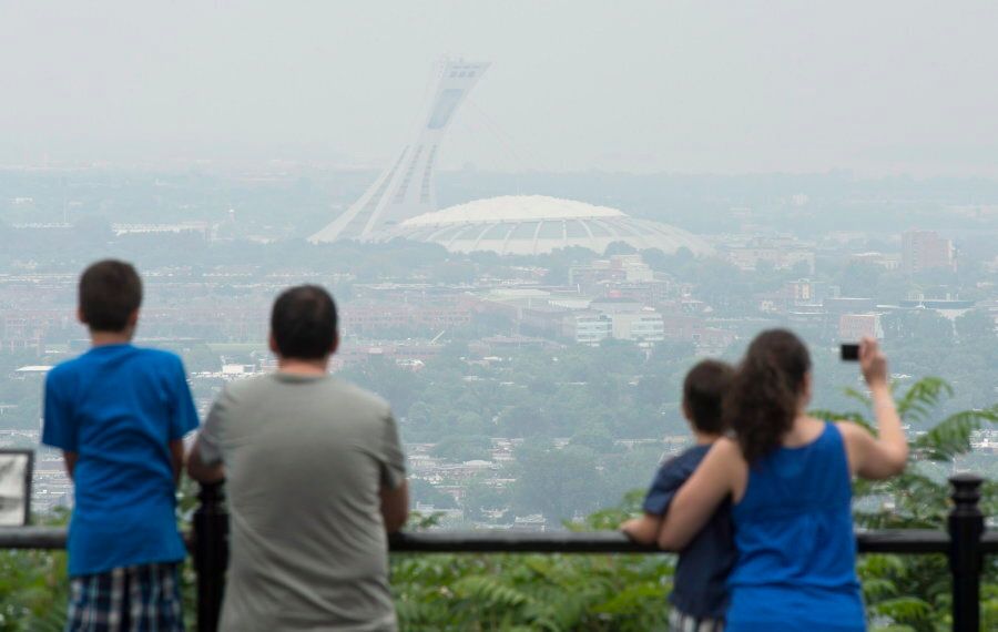 Tourists look over at the Olympic Stadium in the smog-covered city of Montreal on July 3, 2013.