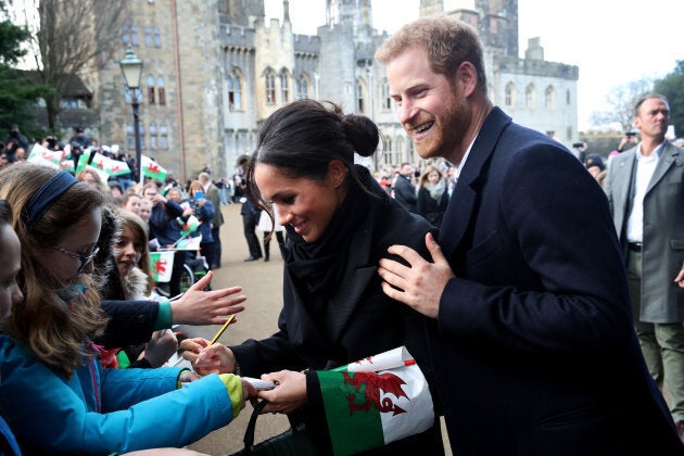 Prince Harry and Meghan Markle sign autographs and shake hands with children at Cardiff Castle on Jan. 18.