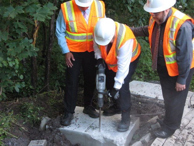 Former Montreal Mayor Denis Coderre uses a jackhammer to destroy a concrete foundation laid for an unauthorized community mailbox at the entrance to Anse-a-l'Orme Nature Park on on Aug. 13, 2015.