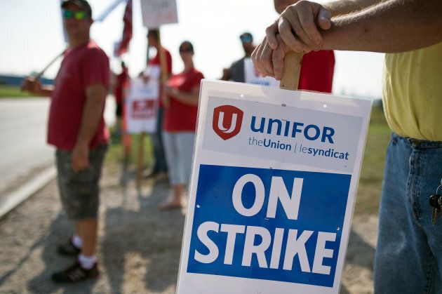 Employees and Unifor members hold 'On Strike' signs outside the General Motors Co. plant in Ingersoll, Ontario, on Sept. 20, 2017.