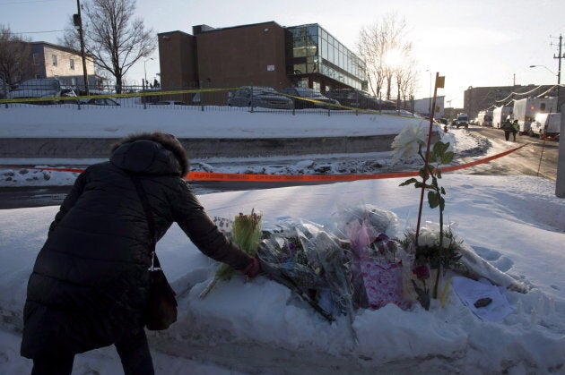 A woman places flowers near a mosque where a shooting the previous night left six people dead in Quebec City.