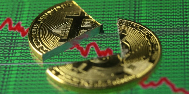 Broken representation of the Bitcoin virtual currency, placed on a monitor that displays stock graph and binary codes, are seen in this illustration picture, Dec. 21, 2017.