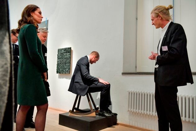 The Duke of Cambridge tries out a chair as Catherine and others look on.