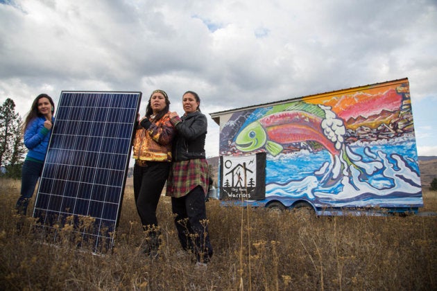 Kanahus Manuel, Mayuk Manuel and Melina Laboucan-Massimo hold the solar panels that have been installed on one of the tiny homes that members of the Secwepemc Nation are building on Kinder Morgan's path through their unceded territory.