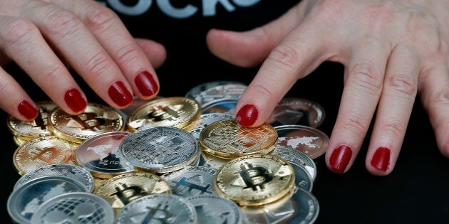 In this photo illustration, a woman shows different visual representations of cryptocurrencies, Ripple, Bitcoin, Litecoin and Ethereum on Feb. 01, 2018 in Paris.