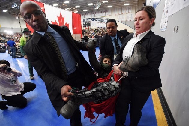 A protester is carried out of the building by police officers during a public town hall with Prime Minister Justin Trudeau (not shown) in Nanaimo, B.C., on Feb. 2, 2018.