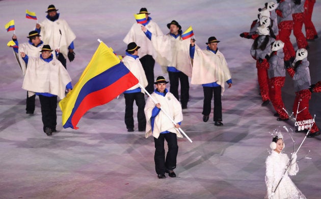 Flag bearer Pedro Causil of Colombia leads the team.