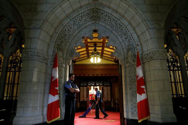 A worker vacuums in the Senate chamber on Parliament Hill in Ottawa on May 3, 2016