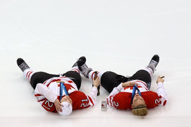 Haley Irwin, left, and Meghan Agosta lie on the ice and celebrate winning the gold medal with a beer and a cigar.