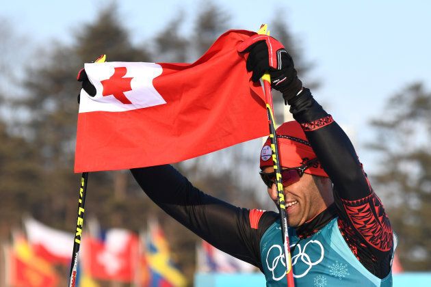 Tonga's Pita Taufatofua holds up his national flag after crossing the finish line during the men's 15km cross country freestyle at the Alpensia cross country ski centre during the Pyeongchang 2018 Winter Olympic Games on Feb.16, 2018 in Pyeongchang.