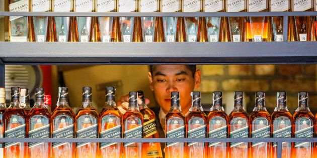 A bartender takes a bottle of Johnnie Walker whisky at Barmaglot bar in Almaty, Kazakhstan June 22, 2017.