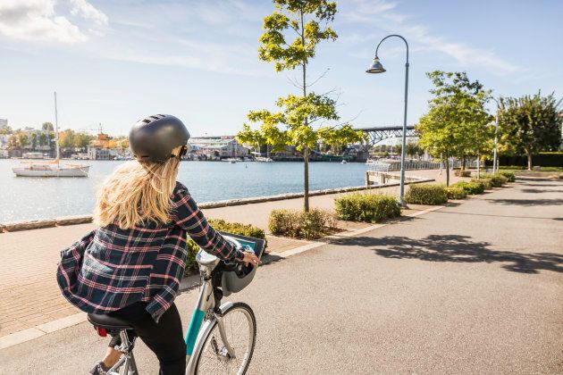 A woman rides a bicycle along the Vancouver waterfront.