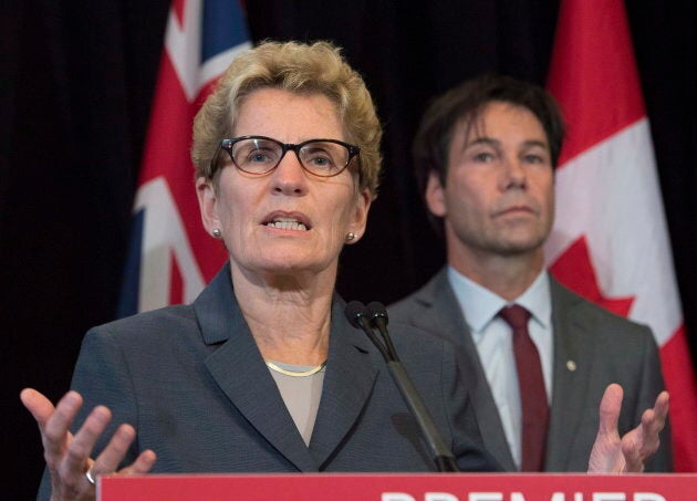 Ontario Premier Kathleen Wynne, left, speaks as now-former Health Minister Eric Hoskins looks on.