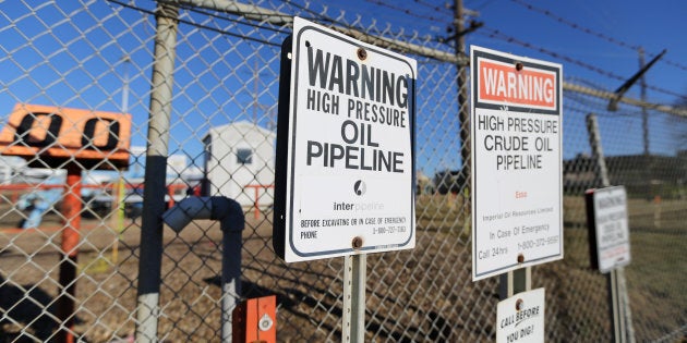 Signs warning of the presence of oil pipelines are seen on a fence at