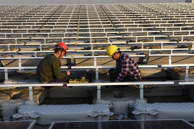 Workers install solar panels at a floating solar plant in Huainan, Anhui province, China.