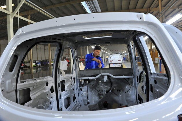 An employee assembles an electric car along a production line at a factory in Qingzhou, Shandong province, China.