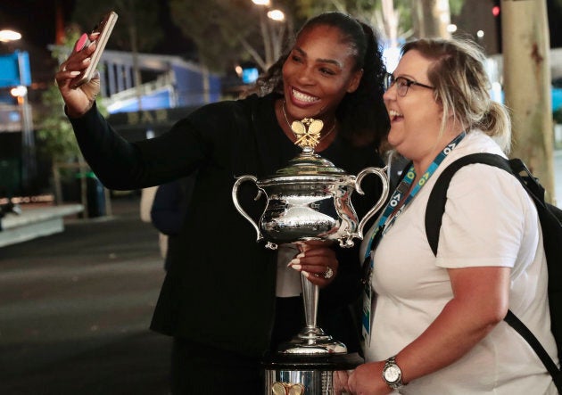 Tennis - Australian Open - Melbourne Park, Melbourne, Australia - early 29/1/17 Serena Williams of the U.S. holds the Women's singles trophy as she poses with a fan Kate Salemme, after winning her final match.