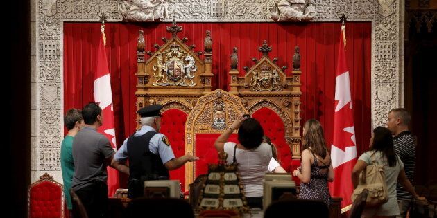 A guard talks to people touring the Senate chamber on Parliament Hill in Ottawa on July 24, 2015.