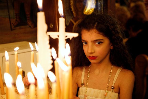 A girl stands near candles inside Al-Saleeb church during Palm Sunday in Damascus, Syria on April 9, 2017.