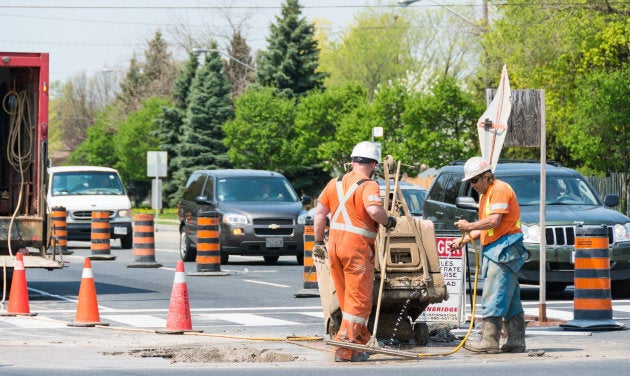 Two workers do repair work on a Toronto roadway.