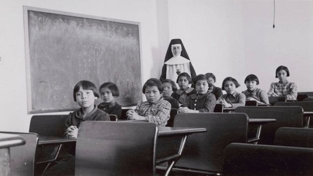 A group of students and a nun pose in a classroom at Cross Lake Indian Residential School in Cross Lake, Man. in a February 1940 archive photo.