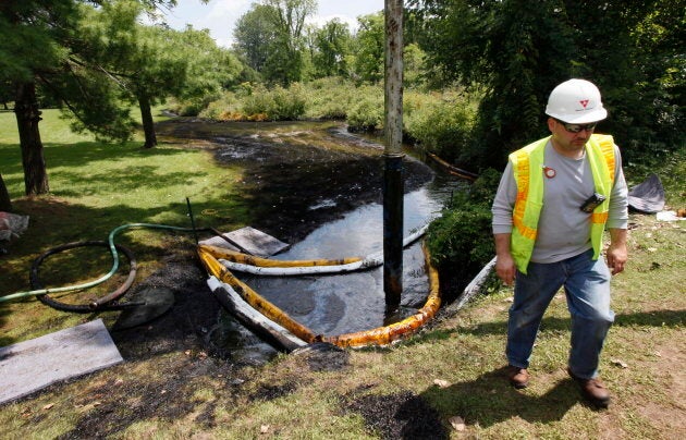 In this July 29, 2010 photo, a worker monitors the water in Talmadge Creek in Marshall Township, Mich., near the Kalamazoo River as oil from a ruptured pipeline is vacuumed out the water.