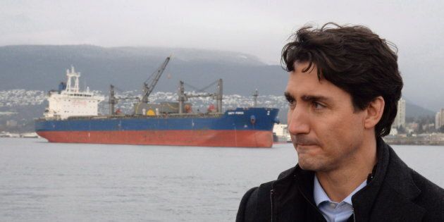 A freighter is seen in the background as Prime Minister Justin Trudeau tours a tugboat in Vancouver Harbour, on Dec. 20, 2016.