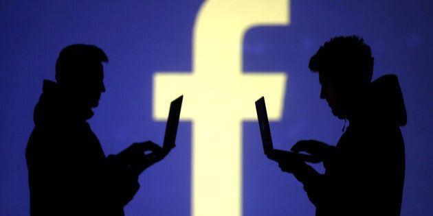Silhouettes of laptop users are seen next to a screen projection of Facebook logo in this picture illustration taken March 28, 2018. A U.S. federal judge ruled on Monday that Facebook must face a class action lawsuit alleging that the social network unlawfully used a facial recognition process on photos without user permission.
