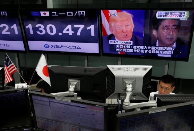 An employee of a foreign exchange trading company works near a monitor showing Japan's Prime Minister Shinzo Abe, right, and U.S. President Donald Trump, left, in a television news report.