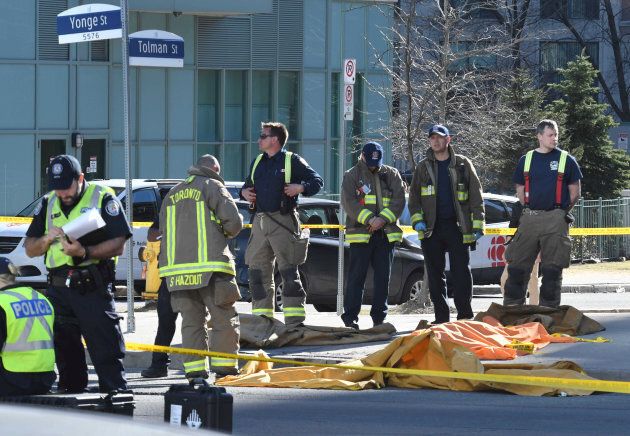 Firefighters stand near a covered body after a van struck multiple people in Toronto on April 23, 2018.